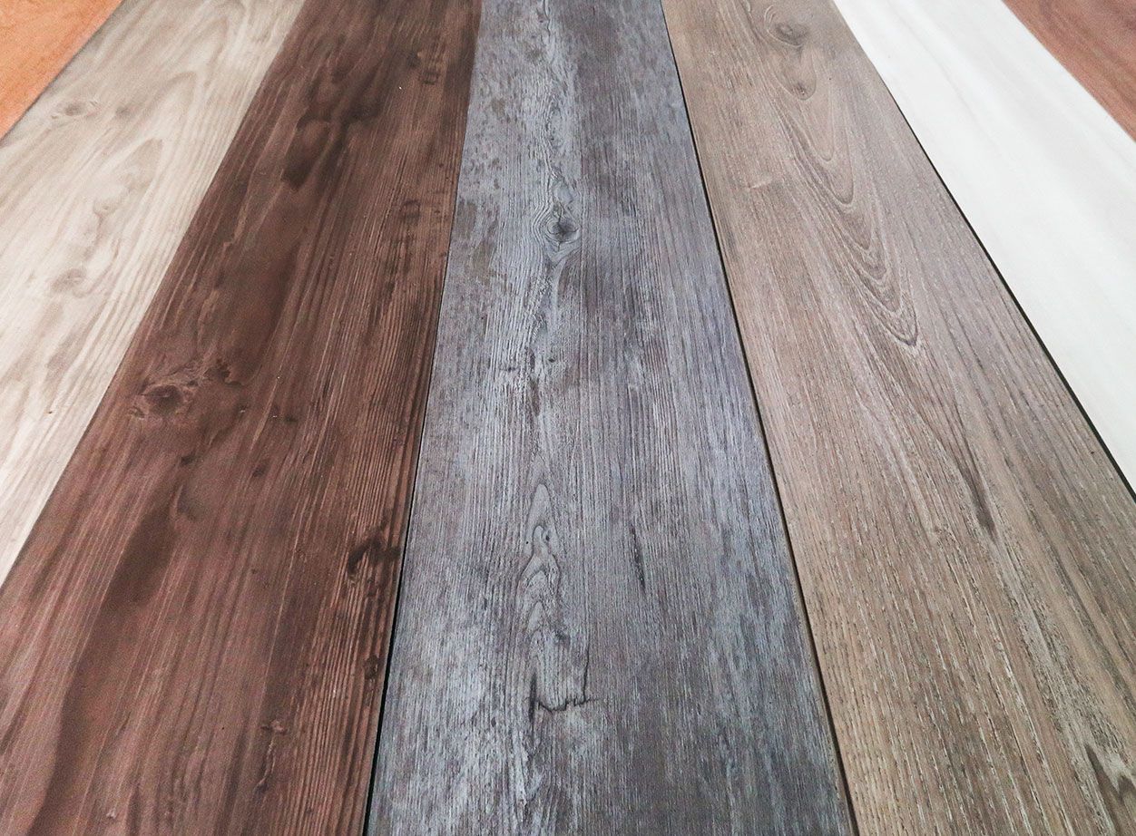 Verschiedene Laminat-Holzfußbodenoptionen in unterschiedlichen Farben und Texturen auf einem Musterbrett angeordnet